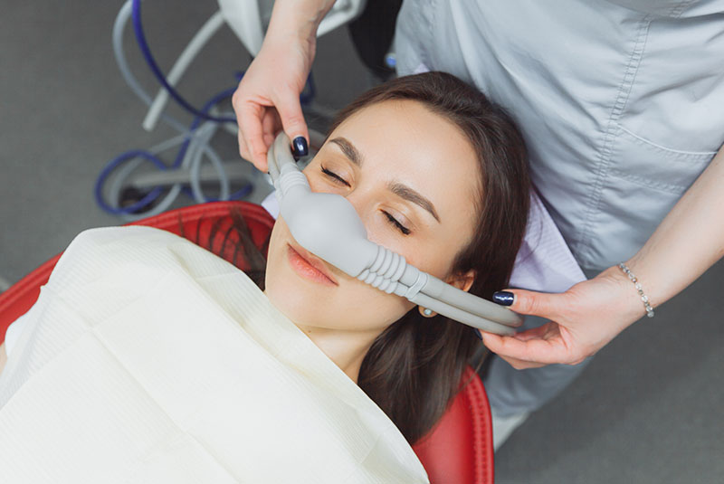 dentist puts inhalation sedative mask on his patient