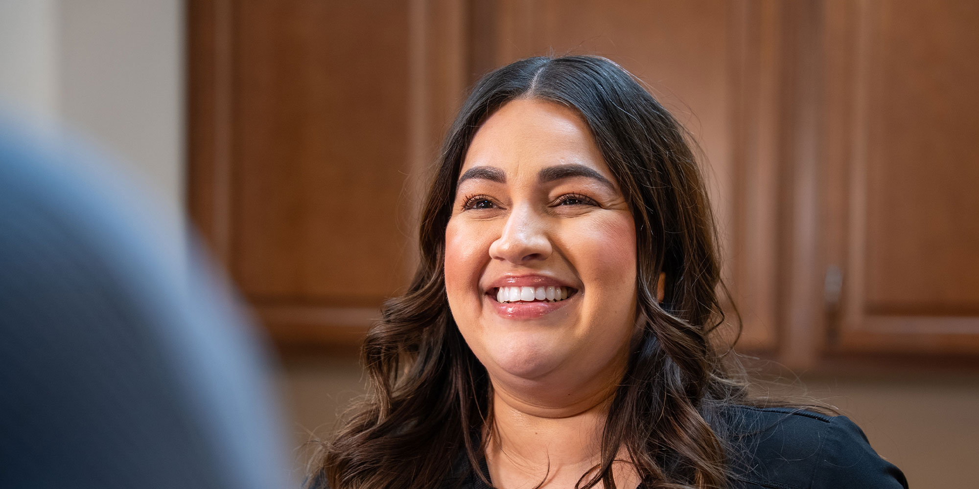 team member smiling brightly while helping patient at the front desk of the dental center
